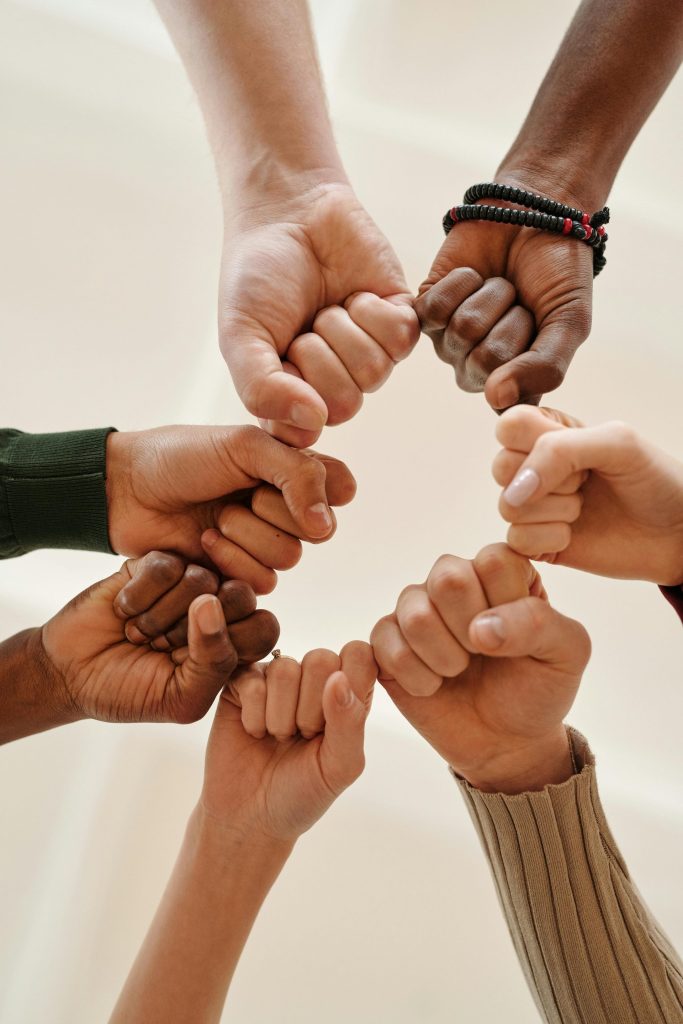 Manos de diversas personas chocando los puños, simbolizando unidad y trabajo en equipo.